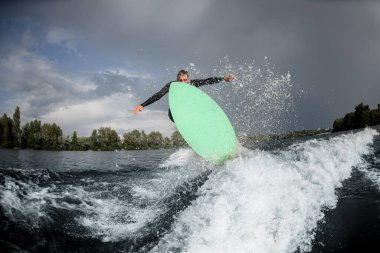 Nehir dalgasında güçlü bir adam zıplıyor.