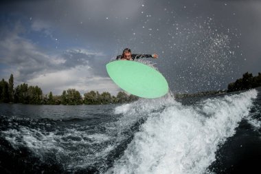 Nehirde sörf tahtasında zıplayan güçlü bir adam.