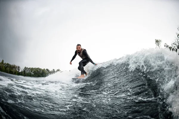 Cara monta na prancha de surf para baixo onda e toca a água — Fotografia de Stock