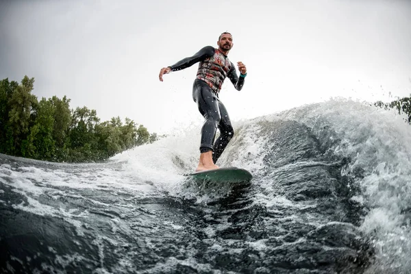 Спортивний чоловік катається на дошці для серфінгу на хвилях позаду човна . — стокове фото