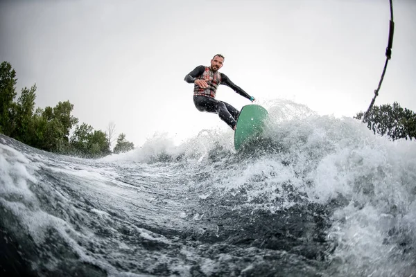 Blick auf gut gelaunte Surfer, die bei sonnigem Wetter schäumende Flusswelle vom Motorboot aus reiten. — Stockfoto