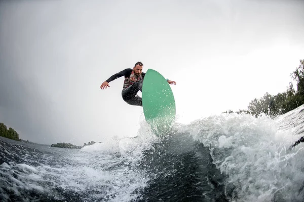 Homem corajoso pulando em wakeboard brilhante para baixo da água do rio — Fotografia de Stock