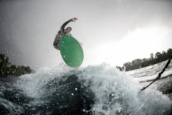 Cara pulando em wakeboard brilhante pela água do rio — Fotografia de Stock