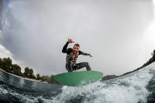 Homem atlético se divertindo saltar na onda na prancha de surf no dia de verão — Fotografia de Stock