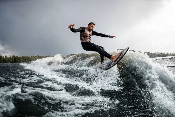 Jovem bonito monta uma onda com sua prancha de surf. . — Fotografia de Stock