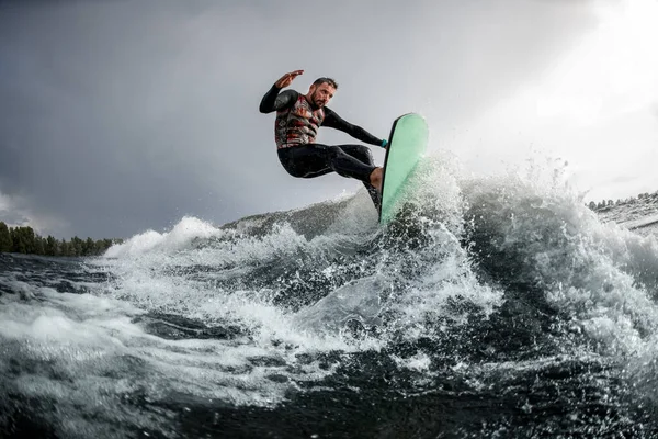 Atlético cara se divertindo saltar na onda na prancha de surf no dia de verão — Fotografia de Stock