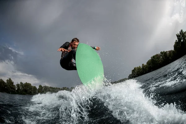 Homem forte pulando em wakeboard brilhante na água do rio — Fotografia de Stock