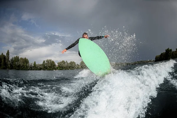 Nehir dalgasında güçlü bir adam zıplıyor.