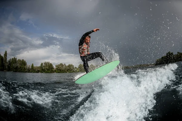 Hombre valiente saltando sobre el wakeboard brillante en la ola del río —  Fotos de Stock