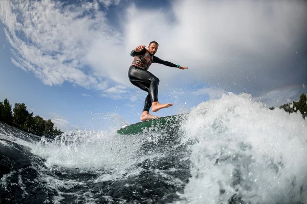 Sporty guy having fun rides vague sur planche de surf — Photo