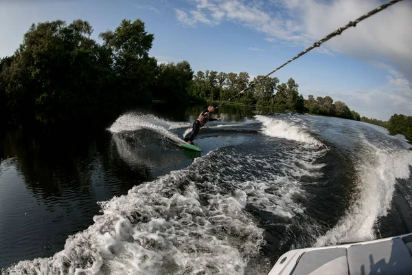 Sportig gue rider på wakesurf genom vågorna på vatten ombord — Stockfoto