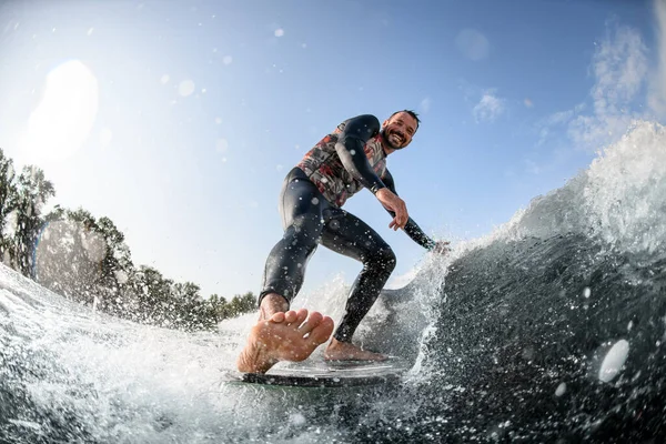 Felice uomo divertendosi cavalca onda sulla tavola da surf e tocca l'acqua — Foto Stock