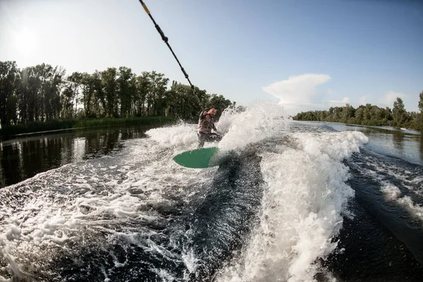 Sportif guy manèges à travers les vagues sur planche d'eau — Photo