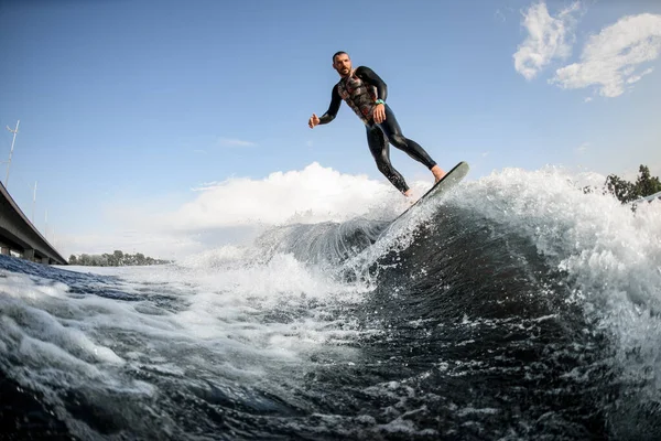 Mann surft auf Surfbrett-Pfaden hinter Boot. Wakesurfen auf dem Fluss — Stockfoto