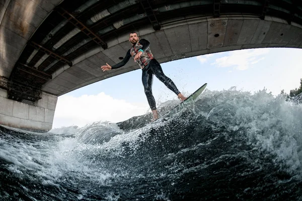 Homem wakesurfer em wetsuit em surfboard passeios na onda. — Fotografia de Stock
