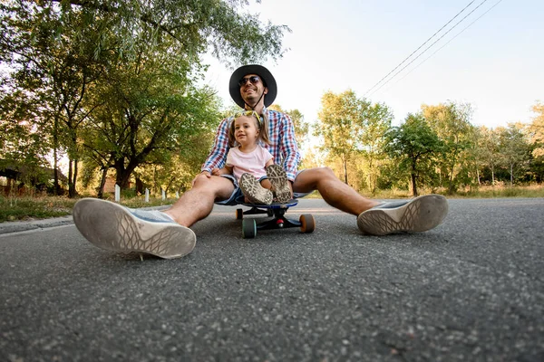 Gelukkig vader rustend op skateboard met zijn dochter — Stockfoto