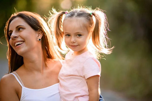 Portrait de petite fille blonde qui s'assoit dans les bras de sa mère — Photo