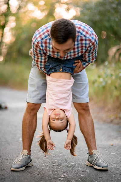 Молодой человек веселится с маленькой девочкой и держит ее вверх ногами. — стоковое фото