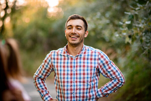 portrait of man with dark hair in plaid shirt in the park