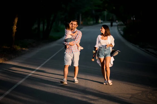 Gelukkige vrouw en man met klein kind wandelen in het avondpark — Stockfoto