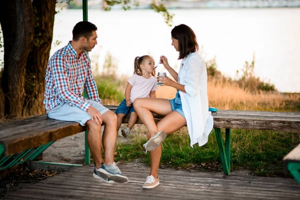 Mooie vrouw voeden met lepel haar kleine schattig dochter zitten op bank — Stockfoto