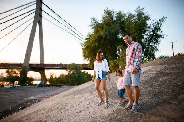 Gelukkig vader en moeder loopt met kleine dochter in roze t-shirt op zomerdag — Stockfoto