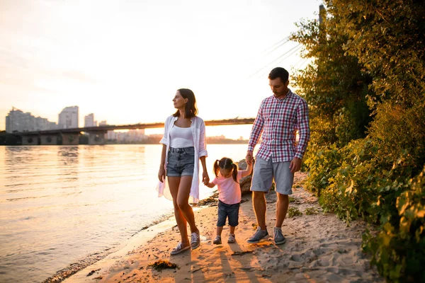 Jonge familie koppel en kleine dochter wandelen langs de zandbank — Stockfoto