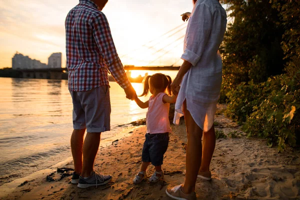 Rear view family couple with kid are walking along the sandy river bank — Stock Photo, Image