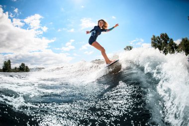 Neşeli genç kadın sörf tahtasında aktif olarak sörf yapıyor