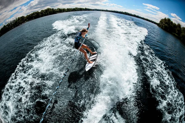 ウェイクサーフィンに乗る女性の高い角度ビューモーターボートのロープを保持 — ストック写真