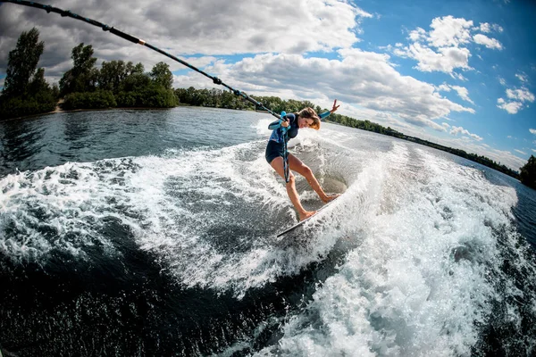 Cheerful woman rides the river wave holding the rope of motor boat — Stock Photo, Image