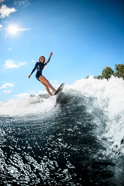 Kilátás gyönyörű mosolygós nő aktívan lovagolni szörfdeszka a hullám — Stock Fotó