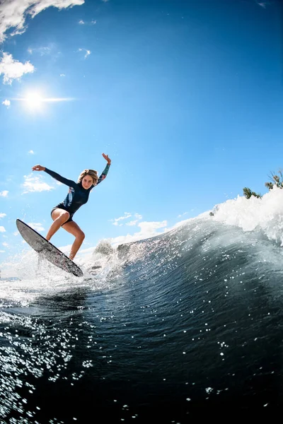 青い空を背景に川の波に乗る水着姿の女. — ストック写真