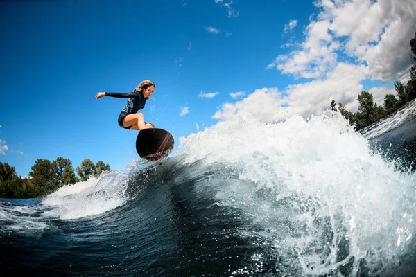 Donna su tavola da surf che salta sopra l'onda — Foto Stock