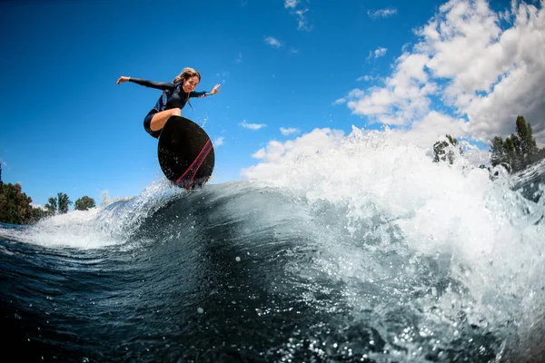 Vista de la joven mujer enérgica en la tabla de surf saltando sobre la ola —  Fotos de Stock