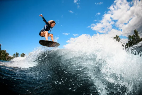 Schöner Blick auf junge Frau auf Surfbrett, die über die Welle springt — Stockfoto
