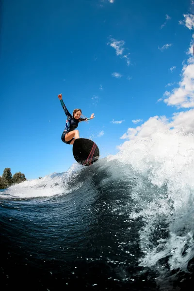 Glückliche Frau cool springen auf der Welle mit Surfbrett — Stockfoto