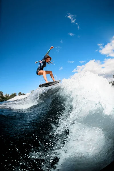 Jovem mulher alegre habilmente pulando com prancha de surf na onda — Fotografia de Stock