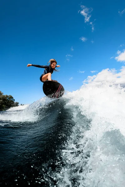 Mujer sonriente guapo saltando hábilmente con tabla de surf en la ola —  Fotos de Stock