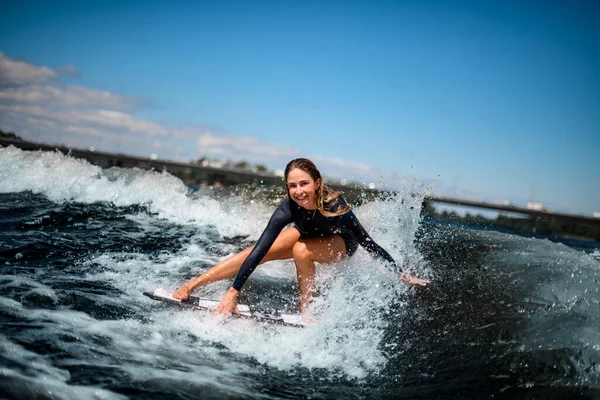 サーフボードに座って手で水に触れるのが楽しい女の子の姿. — ストック写真