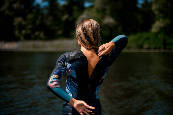 Rear view of woman in wetsuit with the zipper open.