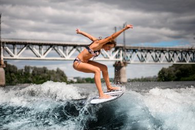Sörf tahtasındaki aktif kadın dalgalarda enerjik bir şekilde geziniyor.
