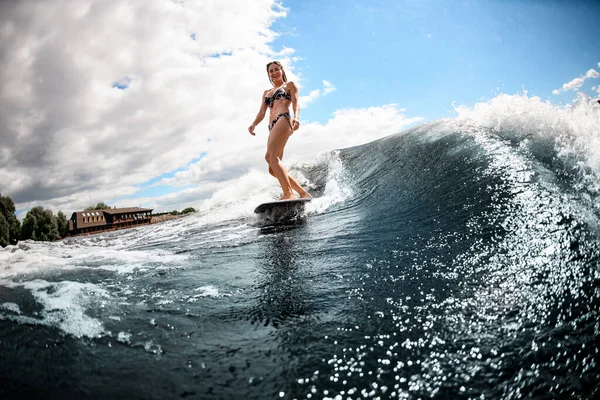 Schöne Frau im Badeanzug steht auf Surfbrett und reitet die Welle hinunter — Stockfoto