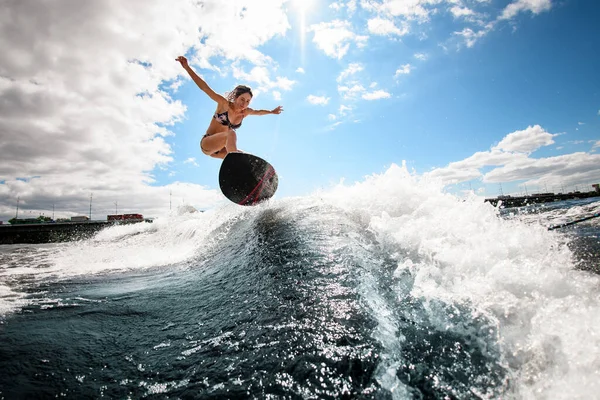 Mulher sorrindo habilmente salta na onda com prancha de surf — Fotografia de Stock