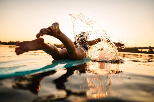 Vista trasera de la mujer acostada en wakeboard remo y salpicaduras de agua con las manos —  Fotos de Stock