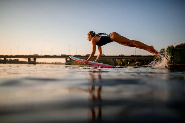 Активная женщина с вейкбордом в стиле серфинга в руках летает над водой — стоковое фото