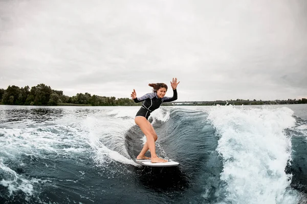 Braunhaarige Frau balanciert auf dem Surfbrett und reitet auf der Welle. — Stockfoto