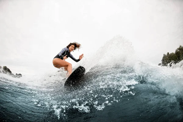 極端なスポーツに従事し、川の波に乗ってボードに乗る水着の女性のビュー — ストック写真