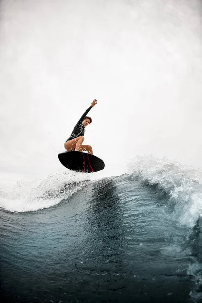 Mujer atlética salta efectivamente con tabla de surf en la ola —  Fotos de Stock