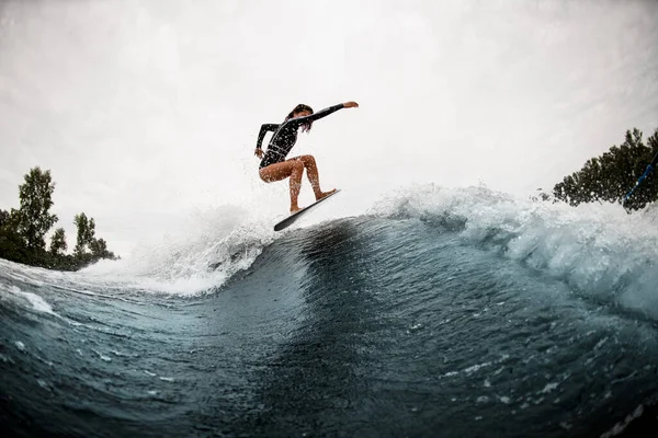 Jovem esportista surfa friamente na prancha de surf e pula na onda — Fotografia de Stock